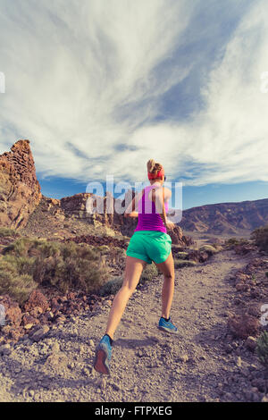 Frau-Berglauf in Bergen auf Feldweg. Schönheit weibliche Läufer Joggen gesundes Training mit Rucksack im Freien in der Natur Stockfoto