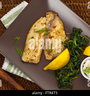 Gebackenes Fischfilet mit sautierten Spinat Stockfoto