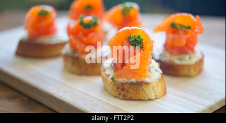 Häppchen mit Lachs und Käse auf Holztisch Stockfoto