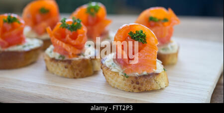 Häppchen mit Lachs und Käse auf Holztisch Stockfoto