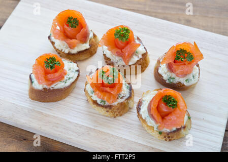 Häppchen mit Lachs und Käse auf Holzbrett Stockfoto