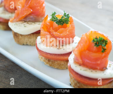 Häppchen mit Lachs und Käse auf Holztisch Stockfoto