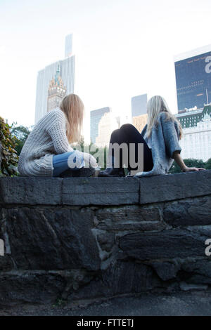 Zwei junge Frauen sitzen im Central Park im Herbst Stockfoto