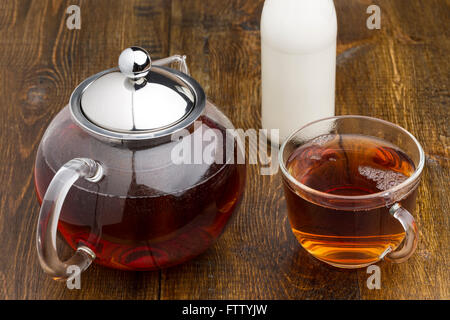 Satz von Glas Teekanne und Tasse Flasche Milch auf Holztisch Stockfoto