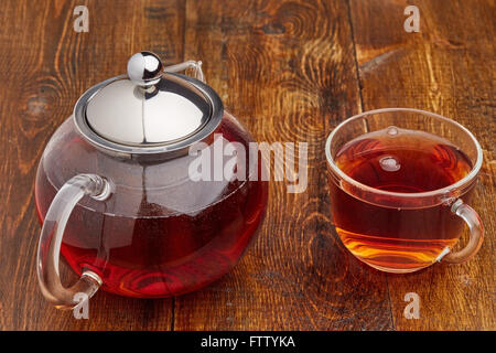 Satz von Glas heißen Teekanne und Tasse Tee auf Holztisch Stockfoto