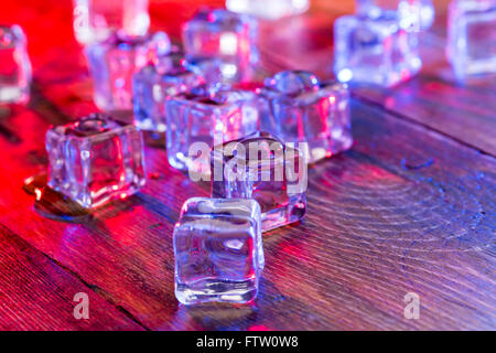 Kälte und Nässe Eiswürfel mit bunten Licht auf Holztisch Stockfoto
