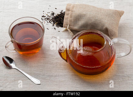 Schwarzer Tee in eine Glasschale und Glas Teekanne gebraut frisch auf einer Serviette aus einer Entlassung Stockfoto
