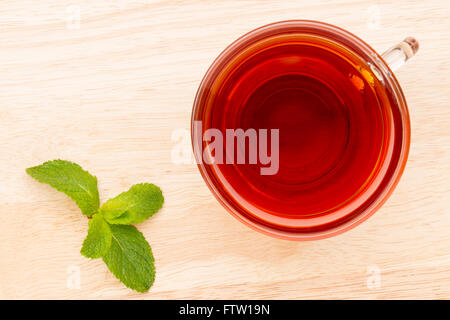 Glastasse Tee mit Pfefferminze auf dem hellen Holztisch Stockfoto