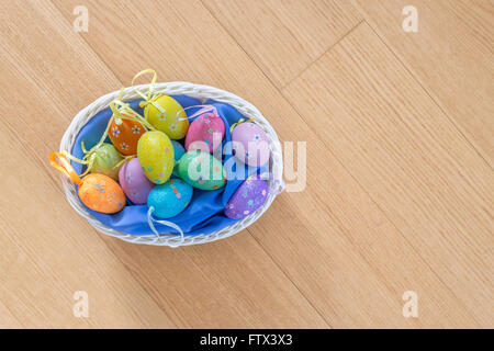 Korb mit Ostereiern auf hölzernen Hintergrund Stockfoto