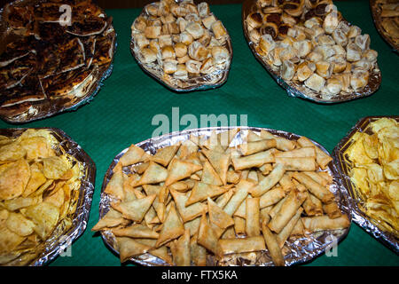 Eine Tabelle auf einer Party oder Feier voller Teller Essen am Buffet Incluidng Frühlingsrollen, Wurstbrötchen, Chips etc. in der Tat typische Party Essen. Stockfoto