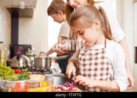 Familie kochen Hintergrund. Mama und Tochter schneiden Zwiebel Salat in der Küche Stockfoto