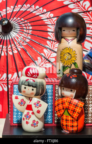 Traditionellen japanischen Kokeshi Holzpuppen und Wagasa Regenschirm im Hintergrund, touristisches Souvenir Stockfoto