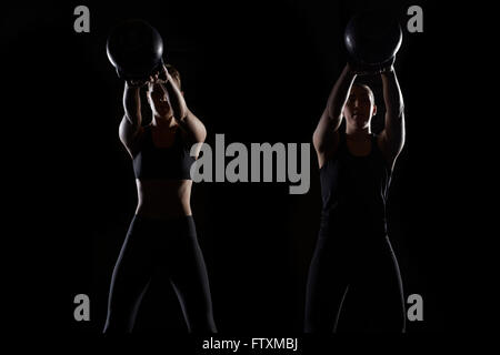 Zwei Frauen heben Kettlebells in Turnhalle Stockfoto