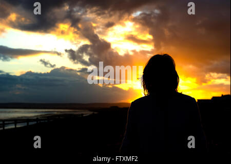 Silhouette einer Frau am Strand bei Sonnenuntergang, Normannen Bay, East Sussex, England, Vereinigtes Königreich Stockfoto