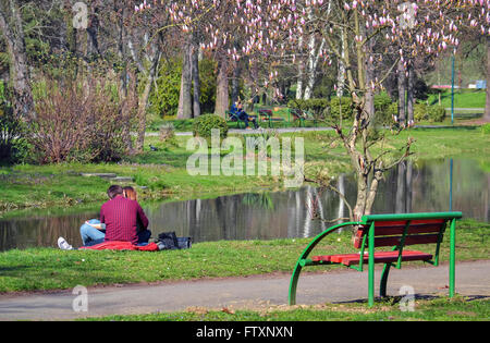 Junges Paar in Liebe sitzen auf dem grünen Rasen im Stadtpark Stockfoto