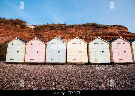 Strandreihe Hütte in Pastell-Farben, rote Rock Cliff Hintergrund, South Devon, UK Stockfoto