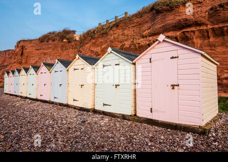 Strandreihe Hütte in Pastell-Farben, rote Rock Cliff Hintergrund, South Devon, UK Stockfoto