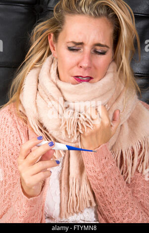 Porträt der blonden Frau eine Erkältung und Thermometer betrachten Stockfoto