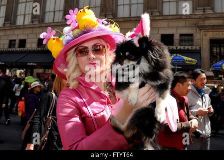 New York City: Elegantl Frau in ein schickes rosa Outfit hält ihren Hund bei der Easter Parade auf der Fifth Avenue Stockfoto