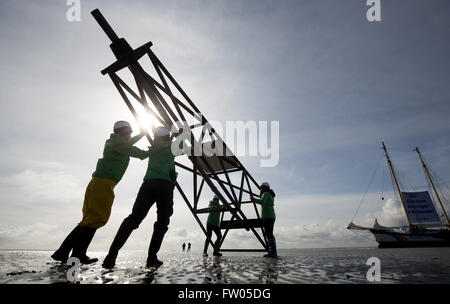 Cuxhaven, Deutschland. 31. März 2016. Aktivisten der Umweltorganisation Greenpeace-Demonstration gegen geplante Ölbohrungen durch Ölgesellschaft Dea Deutsche Erdoel AG im Wattenmeer in der Nähe von Neuwerk aus Cuxhaven, Deutschland, 31. März 2016. Am Donnerstag fuhren die Aktivisten mit dem Greenpeace-Schiff "Beluga II" (R) zu einer geplanten Bohrungen vor Ort in der Nähe des Ölfeldes Mittelplate und Aufmachungen eine sechs Meter hohe hölzerne Bohranlage mit der Meldung "Dea - keine neuen Ölbohrungen im Wattenmeer." Foto: CHRISTIAN CHARISIUS/Dpa/Alamy Live News Stockfoto