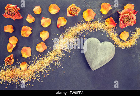 Vintage stilisierten getrockneten Rosen und Herz aus Holz auf Schiefer Hintergrund. Stockfoto