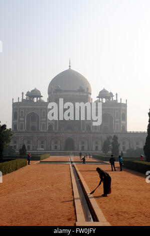 Eine Frau-Kehrmaschine Stäube den Pfad in den Morgen Dunst an Humayun Mausoleum in Neu-Delhi, Indien. Stockfoto