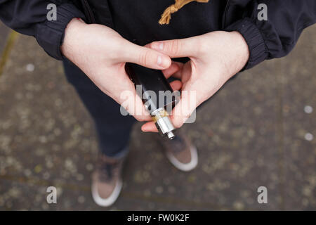 Urbaner Lifestyle Portrait von ein Mann Dampfen in einem städtischen Umfeld mit einem benutzerdefinierten Vape mod Gerät. Stockfoto