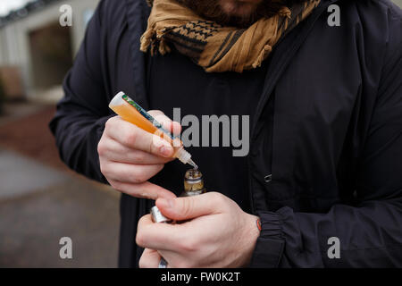 Urbaner Lifestyle Portrait von ein Mann Dampfen in einem städtischen Umfeld mit einem benutzerdefinierten Vape mod Gerät. Stockfoto