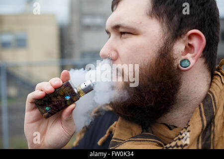 Urbaner Lifestyle Portrait von ein Mann Dampfen in einem städtischen Umfeld mit einem benutzerdefinierten Vape mod Gerät. Stockfoto