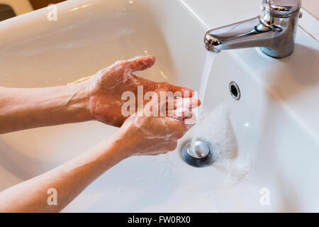 Frau Händewaschen mit Seife in der Spüle Stockfoto