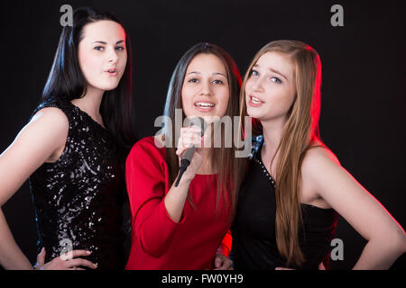 Gruppe von drei elegante schöne junge Sängerinnen singen mit Leidenschaft, Musiktrio Stockfoto