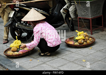 Vietnamesin mit typischen kegelförmigen Hut Verkauf Ananas in der Altstadt von Hanoi, Vietnam Stockfoto