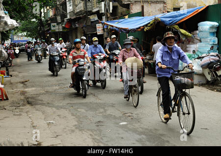 Verkehr mit Roller, Fahrräder und Motorräder in einer Straße mit Geschäften in der Altstadt von Hanoi, Vietnam Stockfoto