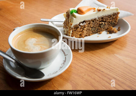 Eine Tasse Kaffee und ein Stück Karottenkuchen serviert in Edinburgh, Schottland. Gekrönt wird die Karotte-Kuchen mit Fondant. Stockfoto