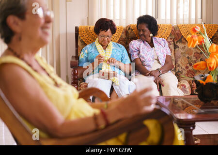 Alte Menschen in geriatrischen Hospiz: Senior Woman auf Sofa im Krankenhaus, stricken mit Wollknäuel zwischen anderen Damen. Stockfoto