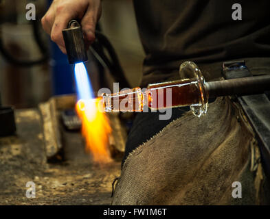 Glas-Handwerker verwendet eine Hand Fackel, um das Stück zu erweichen, dem er arbeitet. Stockfoto
