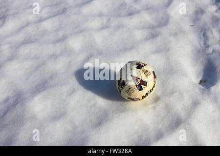 worn-out Fußball auf Schnee Stockfoto