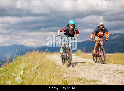 Zwei Mountainbiker mit Helmen fahren auf Schotterstraßen, Mutterer Alm in der Nähe von Innsbruck, Patscherkofel, Tirol, Österreich Stockfoto