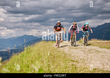 Drei Mountainbiker mit Helmen, Reiten auf einem Schotterweg, Mutterer Alm bei Innsbruck, Tirol, Österreich Stockfoto