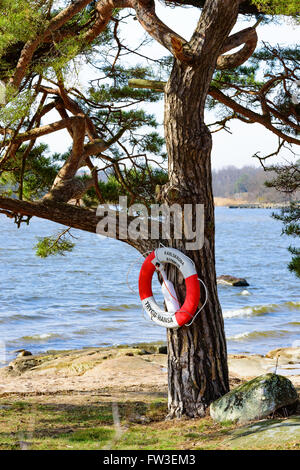 Nattraby, Schweden. 27. März 2016: Ein Rettungsring auf einer Kiefer mit dem Strand und das Meer hinter. Trygg Hansa, eine Versicherung compan Stockfoto