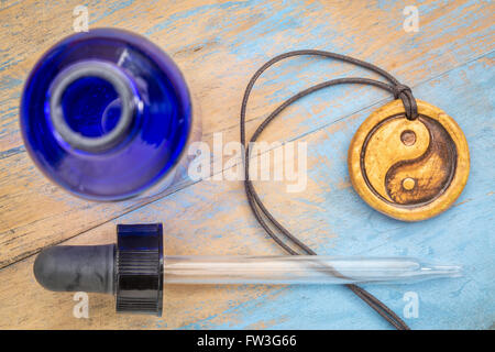 Aromatherapie-Konzept - ätherisches Öl Diffusor Keramik Anhänger mit Yin und Yang Symbol, Pipette und blaue Flasche Stockfoto