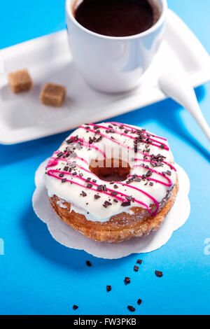 Donut glasiert und Kaffee auf blauem Hintergrund Stockfoto