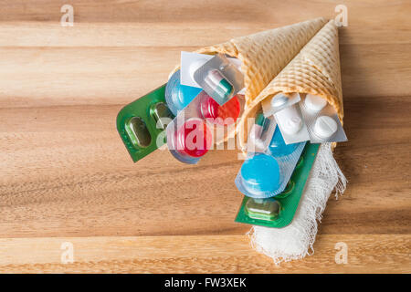 Mischung aus Medikamenten und Pillen in Wafer Kegel auf hölzernen Hintergrund Stockfoto