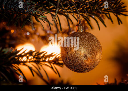 Goldene Weihnachtskugel mit glitzernden Lichtern am Baum hängen Stockfoto