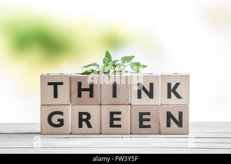 Denken Sie grünes Schild mit einer Anlage auf einem Holztisch Stockfoto