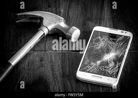 Gebrochene Smartphone und einem Hammer auf den Tisch Stockfoto