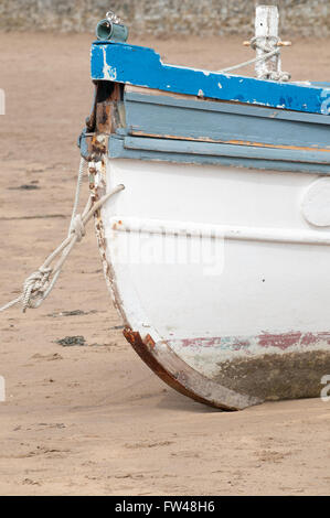 Ein altes Fischerboot vor Anker am Strand bei Ebbe Stockfoto