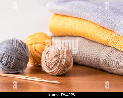 Stränge aus Garn, Stricknadeln und Strickwaren auf Holztisch Stockfoto
