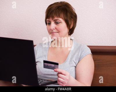 Attraktive reife Erwachsene Frau macht einen Online-Kauf Stockfoto