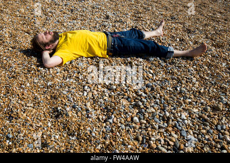 Ein Mann entspannt in der Sonne am Strand von Brighton. 2016 Stockfoto